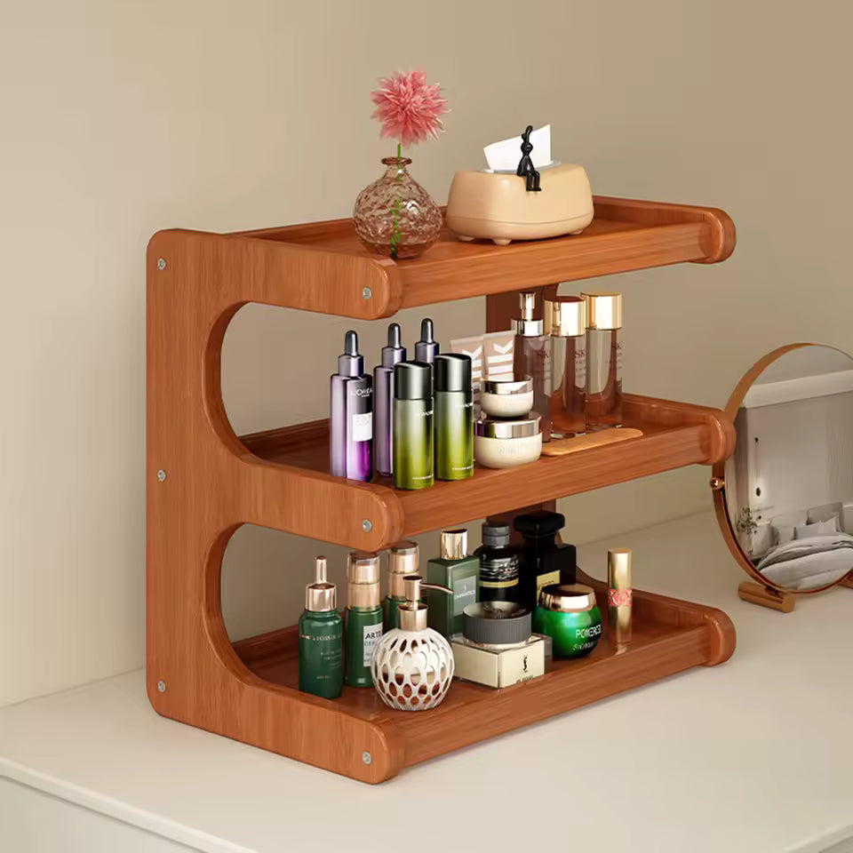 Two-tier brown bamboo desktop organizer on a white vanity, holding various skincare bottles and perfume jars.