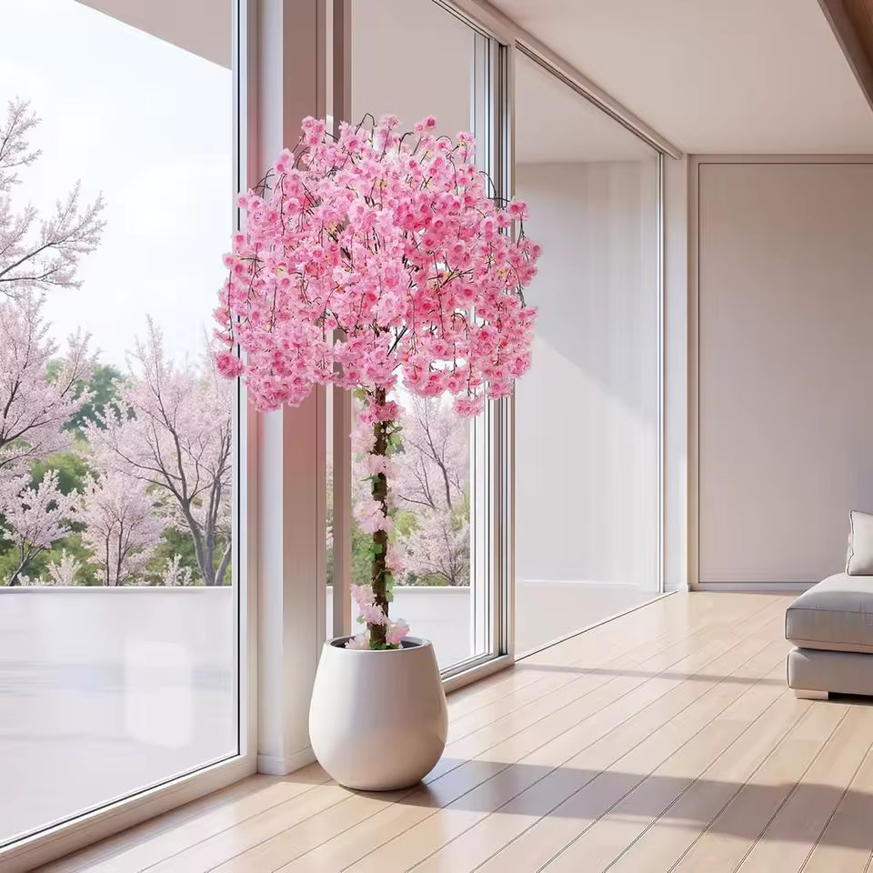 Artificial pink cherry blossom tree in a white ceramic floor vase, modern minimalist interior design with large windows.