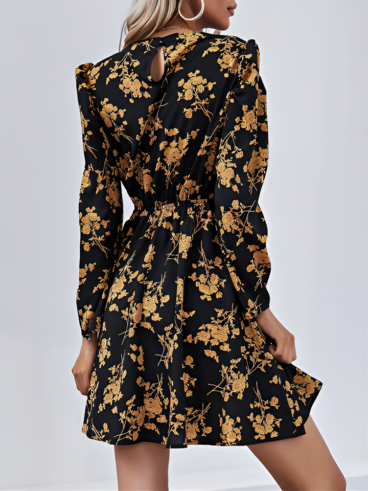 Black dress with gold floral pattern worn by a person on a white background