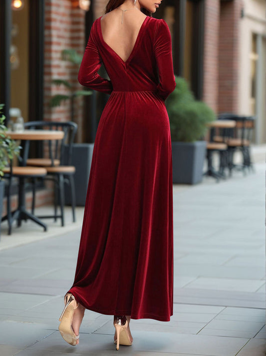 Woman wearing a red velvet dress with a backless design, standing on a sidewalk.