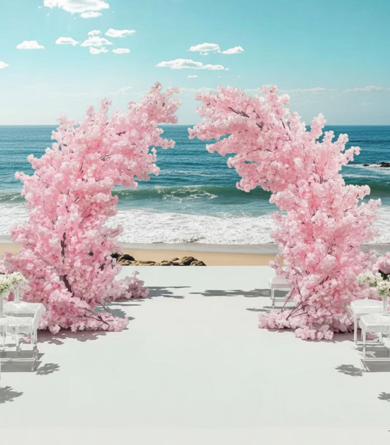 Pink artificial cherry blossom arch on a beach with ocean and sky in the background