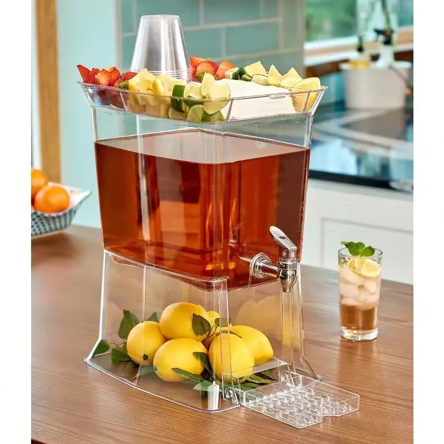 Large 2.5-gallon clear plastic beverage dispenser with a silver tap, featuring a top tray for lemons and napkins, and a drip tray at the base.