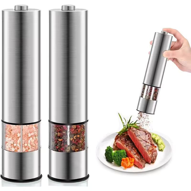 Pair of unbranded brushed stainless steel electric salt and pepper grinders with clear acrylic spice chambers, standing next to a seasoned steak.