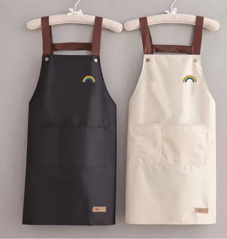 Professional waterproof cotton kitchen apron in black and cream with brown cross-back straps and a small rainbow embroidery on the chest.
