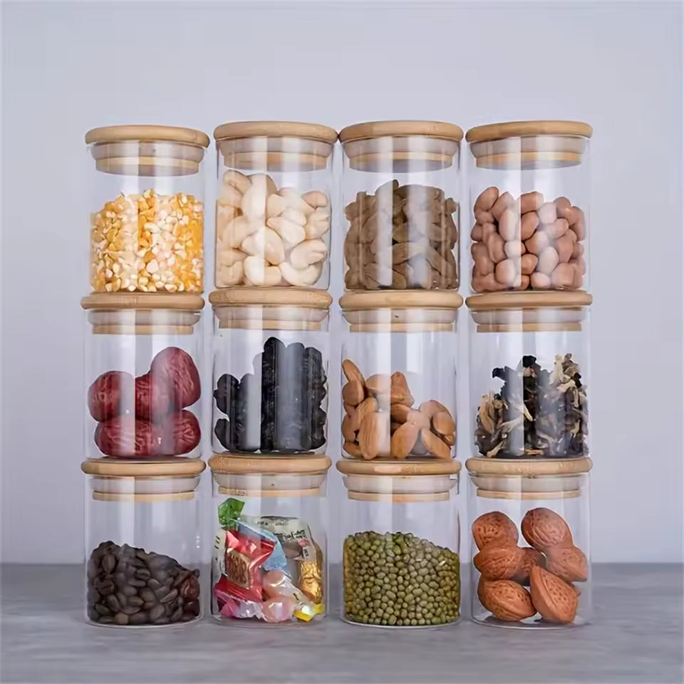 Set of 12 transparent glass food storage jars with airtight bamboo lids, neatly stacked and filled with various grains, nuts, and spices.