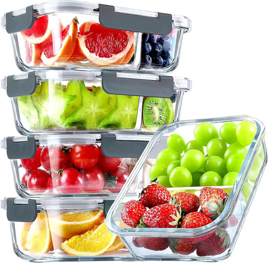 Five 2-compartment glass meal prep containers stacked and filled with fresh fruits like strawberries, grapes, and citrus, showing airtight grey lids.