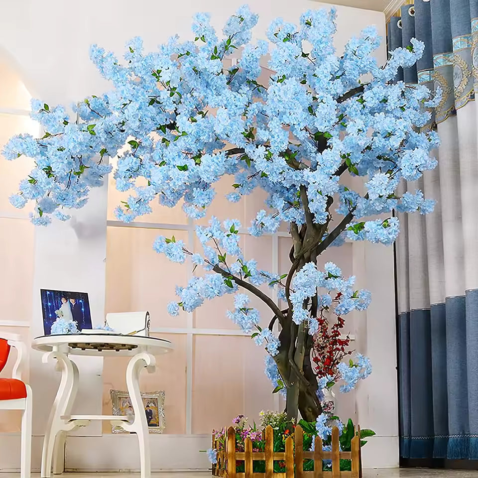 Large artificial blue cherry blossom tree with silk flowers in a wooden fence pot, interior decor for home or events.
