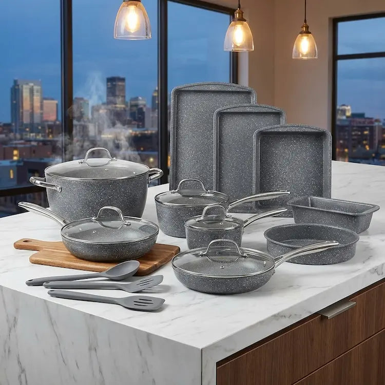 Comprehensive view of the entire 12-piece gray granite culinary and bakeware collection, including pots, pans, lids, and stacked baking sheets, displayed on a luxury modern kitchen counter
