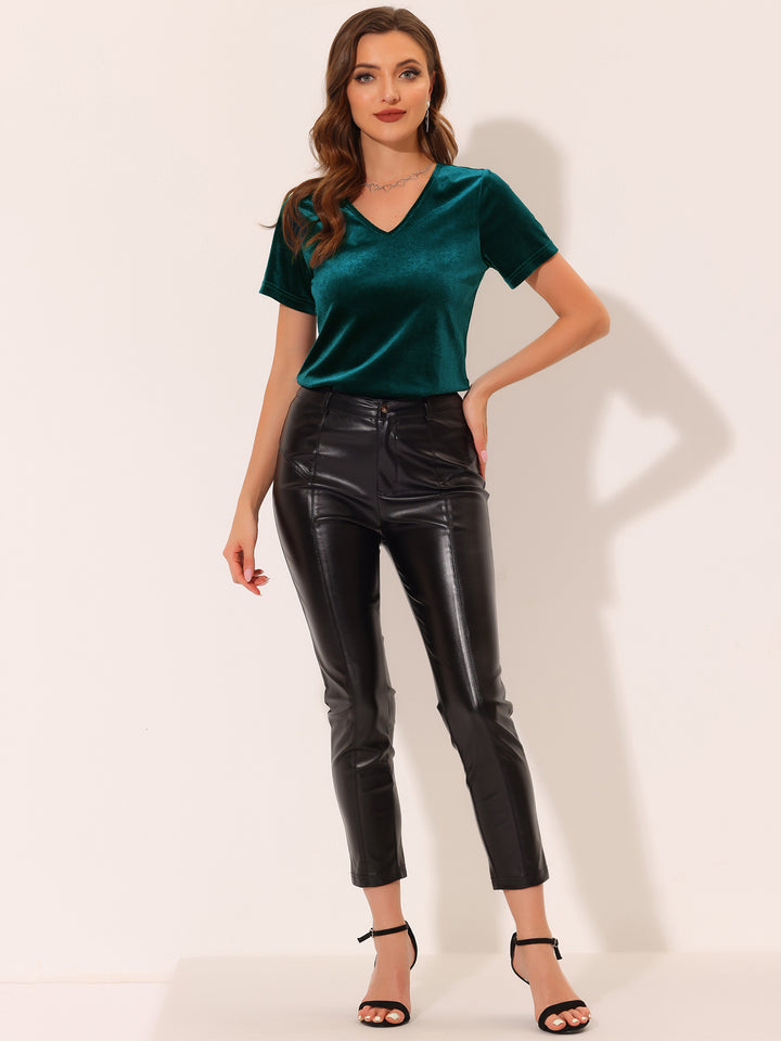 Woman wearing a green top and black leather pants on a white background
