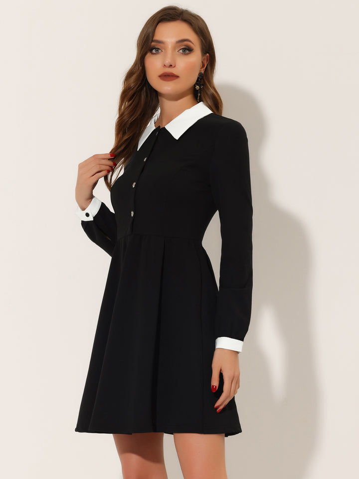 Woman wearing a black dress with white collar and cuffs on a plain background