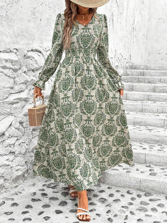 Woman wearing a green floral dress standing on stone steps with a white wall background