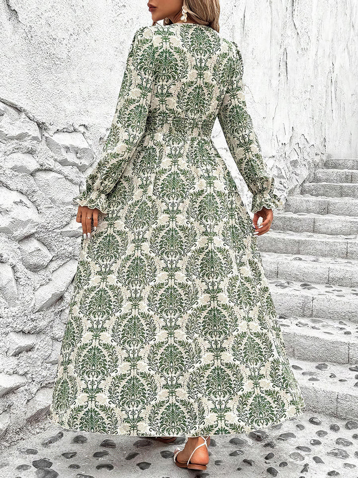 Woman wearing a long green and white patterned dress standing on stone steps.