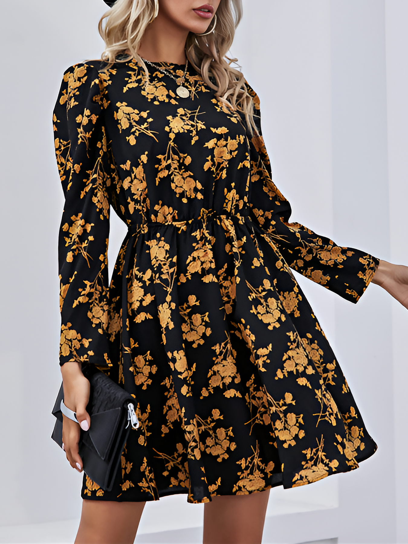 Woman wearing a black dress with gold floral pattern against a white background