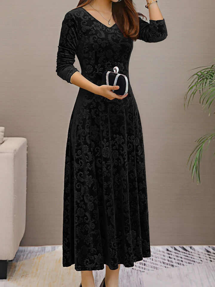 Woman wearing a black floral dress holding a clutch in an indoor setting.