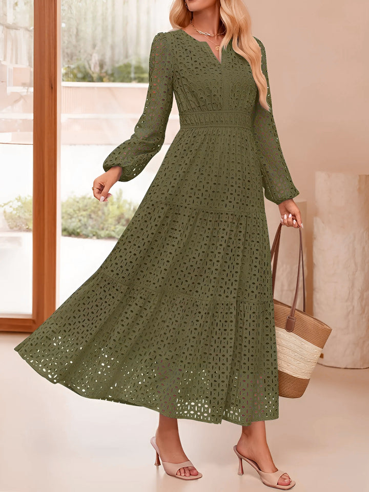 Woman wearing a green lace dress holding a beige handbag indoors.