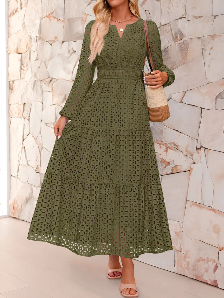 Woman wearing a green lace dress against a stone wall.